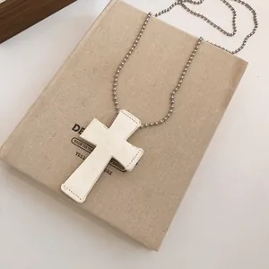 Detail shot of bohemian white leather cross necklace with intricate embossed rose