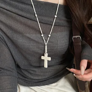 Close-up of a white marble texture stone cross pendant on a beaded necklace chain.