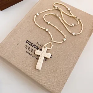 Detailed view of bohemian style beaded cross necklace with stone texture pendant.