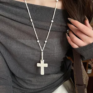 Close-up of white marble-patterned beaded necklace with large cross pendant.