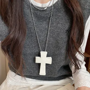Macro view showing the intricate floral engraving on a large white cross pendant necklace