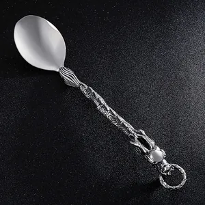Dettaglio di un cucchiaio vintage in acciaio inox con manico a forma di dragone.