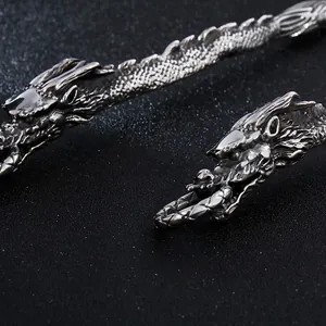 Dettaglio macro del rilievo del drago in argento antico sul manico di posate in acciaio