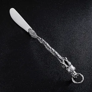 Dettaglio di un coltello in acciaio inox con manico a drago in rilievo vintage.