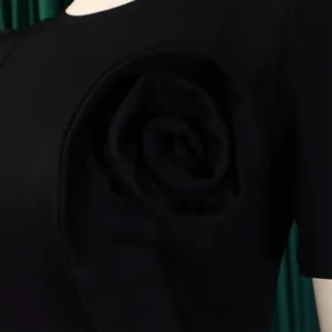 Close-up view of elegant black fabric rose ruffle detail on a stylish fitted dress