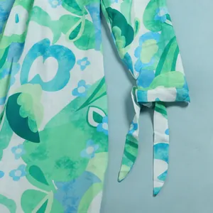 Close-up showing the elegant tie-up cuff detail on a green and blue floral print dress