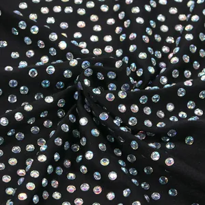 Detalle del tejido de malla negra con pedrería iridiscente en un vestido ajustado.
