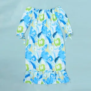 Close-up of vibrant blue and green floral print long sleeve dress with elegant ruffle hem