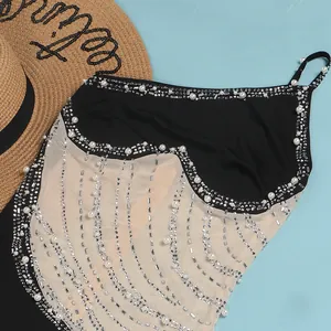 Dettaglio di abito in rete nera con eleganti perle e decorazioni in strass.