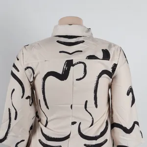 Back view detail of slim fit dress with abstract black line pattern on beige fabric.