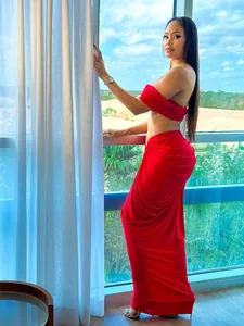 Side view of elegant red strapless two-piece pleated maxi dress with floor-length drape
