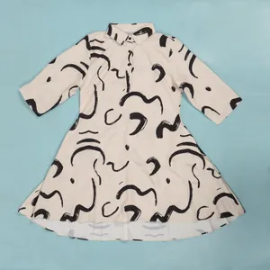 Detailed view of cream-colored shirt dress with unique black abstract brushstroke patterns