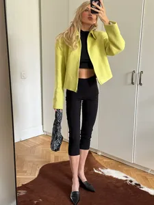 Model wearing black high-waisted capri yoga pants with a stylish lime green jacket