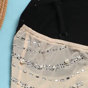 Primo piano dettagliato con perle e strass luccicanti su abito in rete color carne