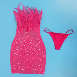 Detailansicht eines pinken Bodycon-Kleids mit Federn, Perlen und Strass auf blauem Grund