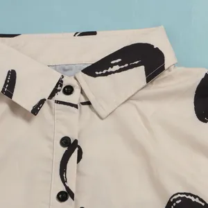 Detailed macro view of beige lapel collar with black buttons on abstract printed dress