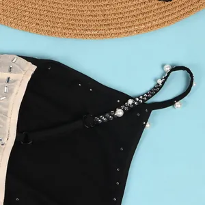 Dettaglio di un abito sexy in rete con spalline eleganti in perle e brillanti strass.