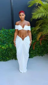 Detail of sexy white two-piece set featuring off-shoulder top and draped floor-length skirt.