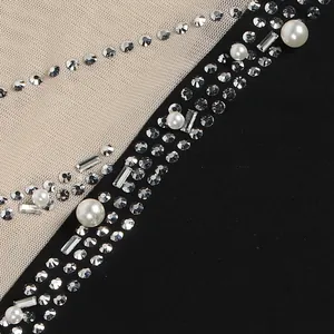 Primo piano di decorazioni con perle e strass su tessuto a rete trasparente per vestiti