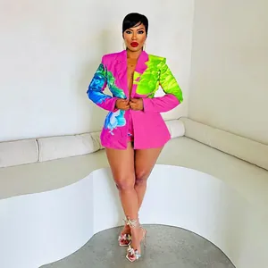 Detail view of vibrant pink blazer and shorts set featuring bold green floral prints.