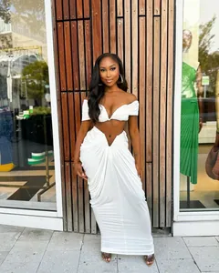 Elegant white ruched two-piece set with off-shoulder crop top and floor-length skirt.