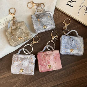 Dettaglio di eleganti portachiavi mini borsa in pelle floreale con finiture in lamina d'oro