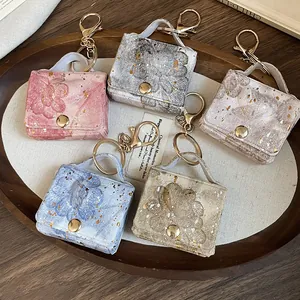 Primo piano di ciondoli mini borsa in pelle con motivi a cuore e floreali dorati