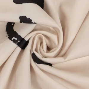 Detail shot showing the soft beige fabric and black pattern of a slim V-neck dress