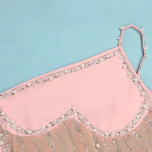 Dettaglio di un abito in rete rosa con eleganti decorazioni in perle e strass
