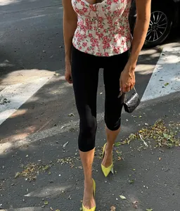 Close-up of black high-waist capri leggings styled with a floral top and yellow heels