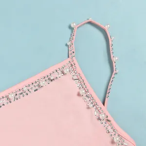 Dettaglio di perle bianche e strass scintillanti sulla spallina dell'abito rosa