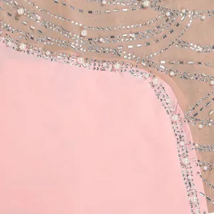 Dettaglio ravvicinato di un abito in rete rosa con eleganti decorazioni di perle e strass.