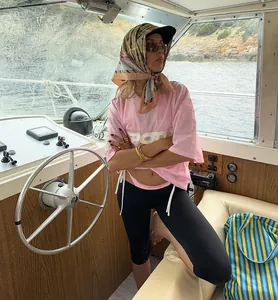 Woman wearing black high-waisted yoga capri leggings on a boat for a lifestyle look.