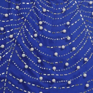 Nahaufnahme der aufwendigen Strass- und Perlenverzierungen auf königsblauem Netzgewebe