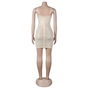 Vista trasera de un sexy mini vestido ajustado beige con patrones de pedrería.