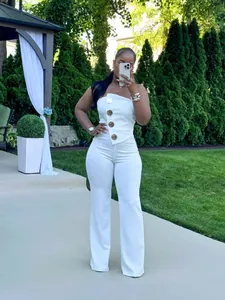 Eleganter weißer trägerloser Jumpsuit mit Goldknöpfen in einer schönen Gartenumgebung