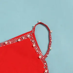 Dettaglio di un abito rosso con eleganti decorazioni di perle e strass sulla spallina.