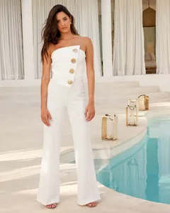 Eleganter weißer trägerloser Jumpsuit mit großen goldfarbenen Knöpfen in Urlaubsatmosphäre
