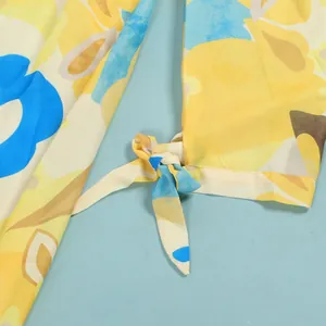 Close-up of a vibrant yellow and blue floral print dress showing a delicate tie-knot sleeve detail