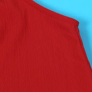Close-up detail of red textured fabric showing high-quality stitching on halter top.
