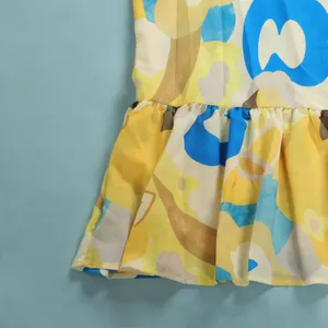 Close-up detail of vibrant yellow and blue floral print dress with a ruffled hemline