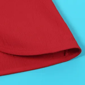 Detail shot of the crinkled red fabric and neatly stitched hem of a halter sleeveless top.