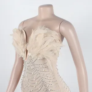 Detail eines sexy beigen Bodycon-Kleides mit Federn Perlen und Strasssteinen.