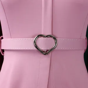 Gros plan d'une robe crayon rose avec une ceinture à boucle en cœur argentée.