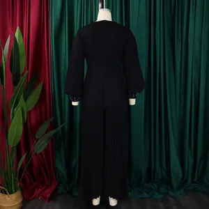 Back view of black pleated wide-leg jumpsuit with elegant beaded cuffs on mannequin