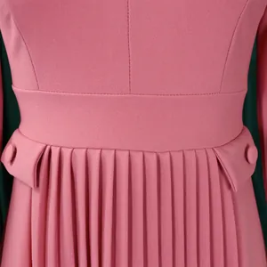 Vue détaillée de la robe rose montrant la jupe plissée et le bouton à la taille