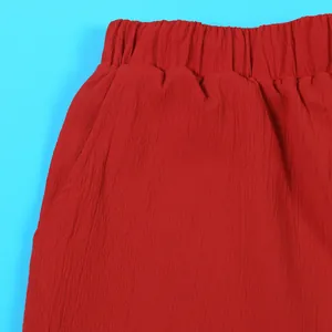 Close-up detail showing the red crinkle fabric texture and elastic waistband of the set pants