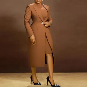Ganzkörperaufnahme eines Models in einem braunen taillierten Mantel und Midi-Kleid