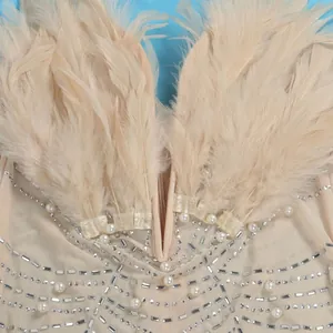 Detailaufnahme eines beigen sexy Kleides mit Straußenfedern, Perlen und funkelnden Strass.