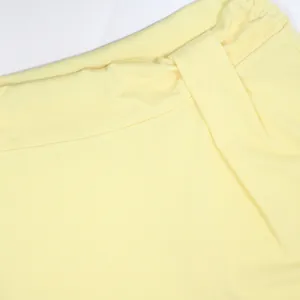 Dettaglio dei pantaloni giallo chiaro a vita alta che mostra la trama del tessuto